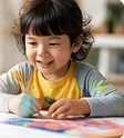 A young child smiling while making crafts