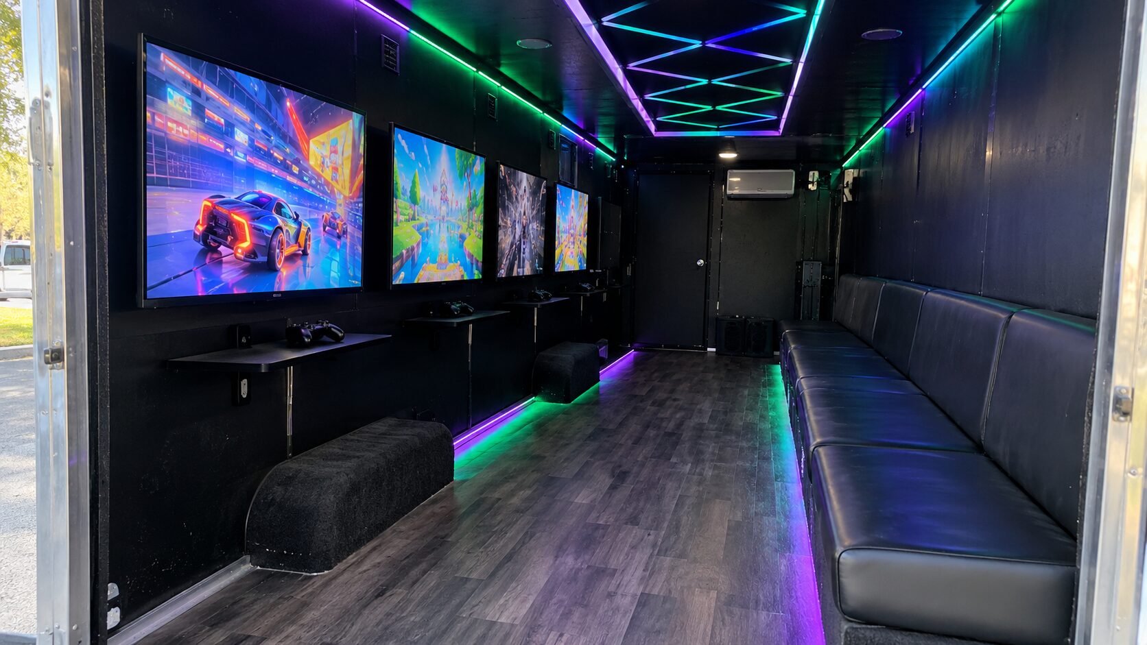 Inside the GameThrilla theater: wall-mounted TVs, a long black bench and LED ceiling lights
