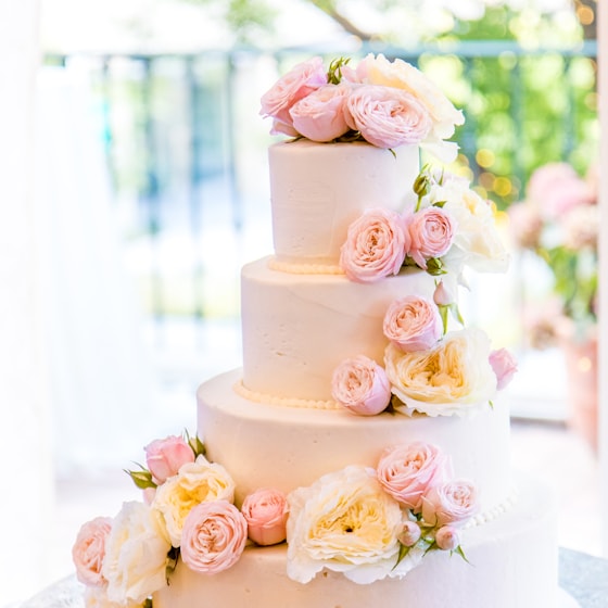 Tiered white wedding cake decorated with fresh roses