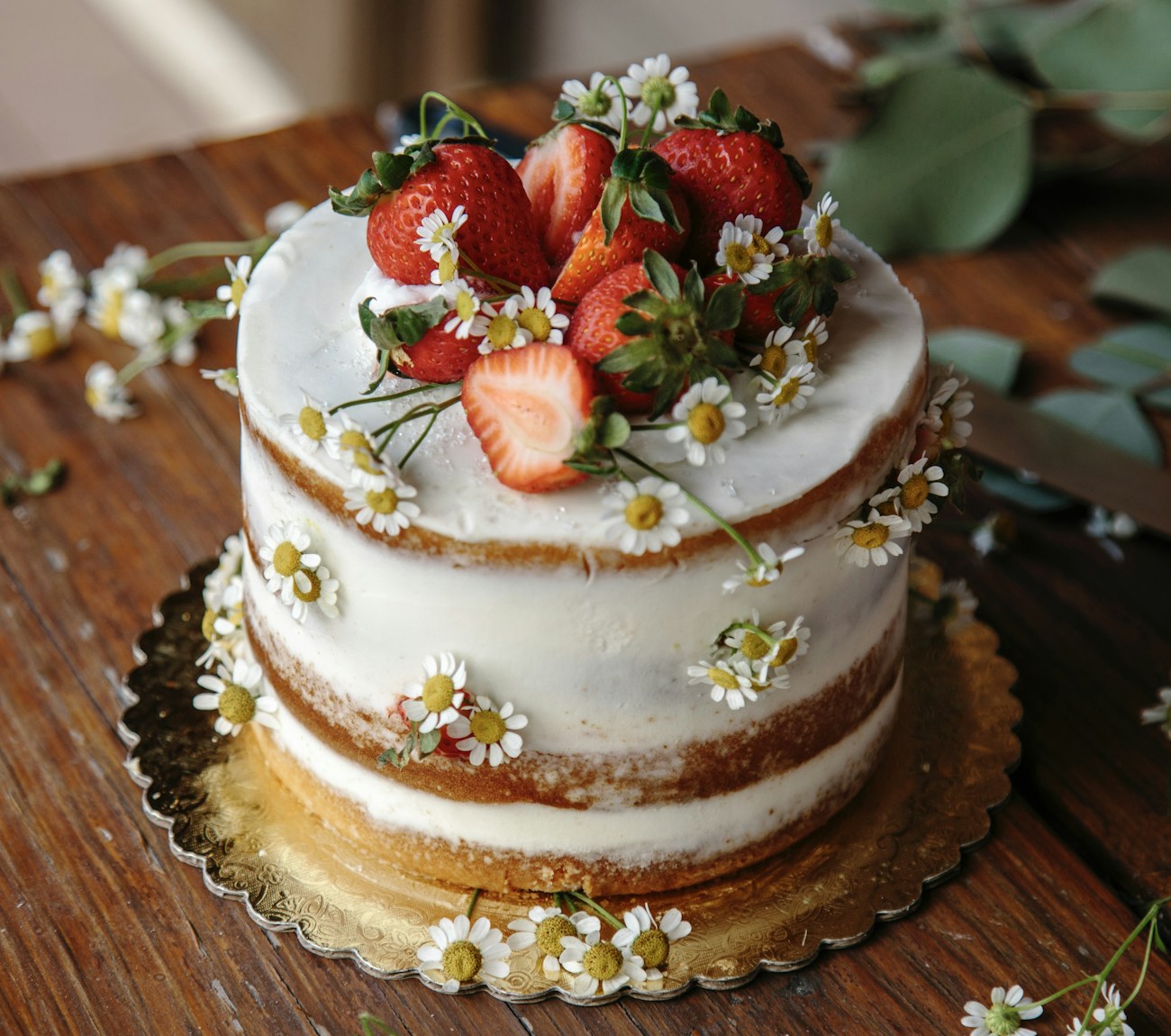 Two-tier Rose Bakery cake topped with fresh strawberries and chamomile flowers