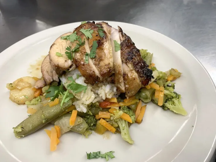 A fish course plated with seasonal vegetables