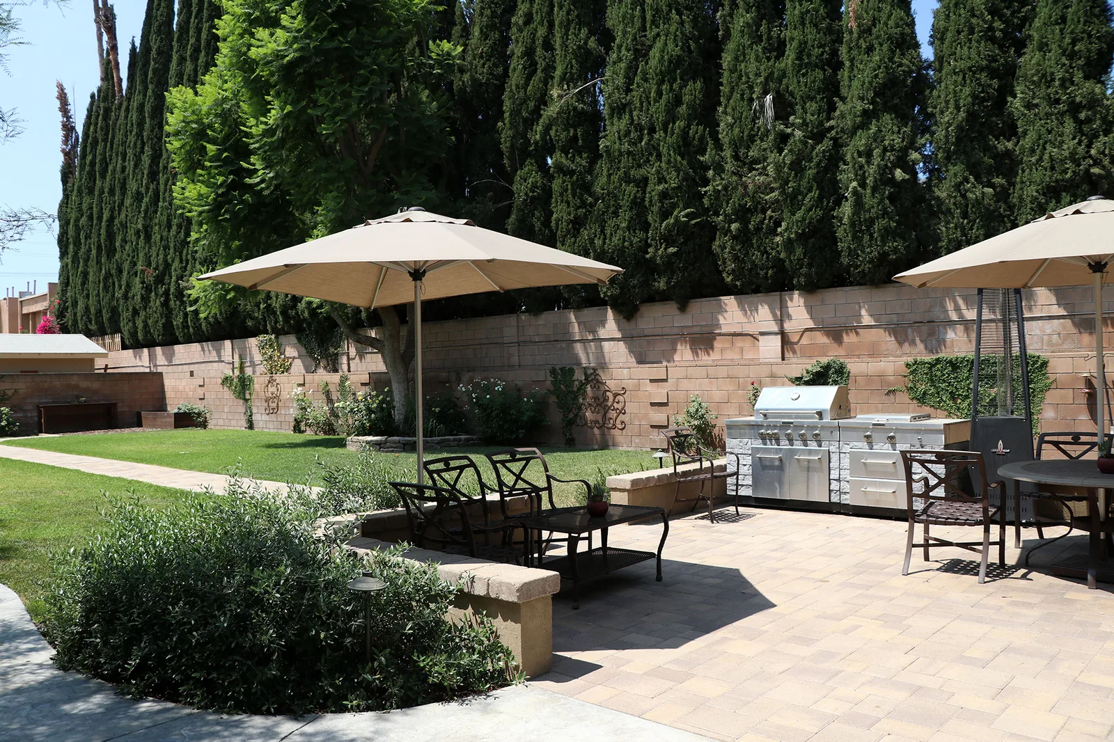 The garden lawn with patio umbrellas and an outdoor barbecue