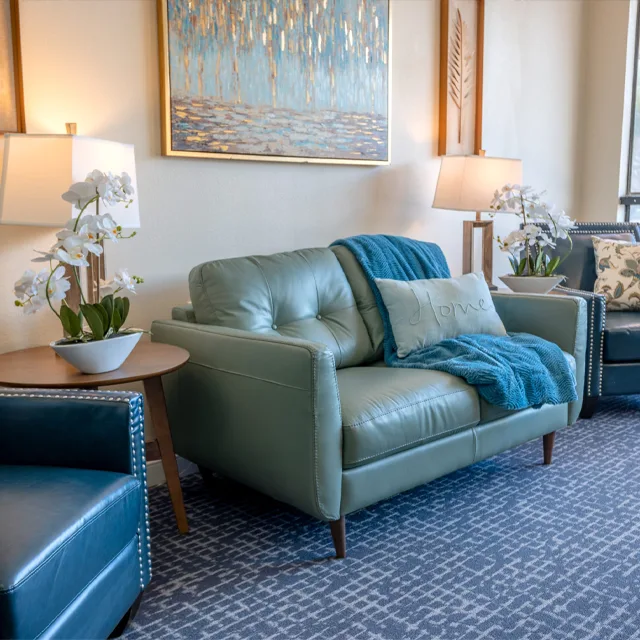 A sofa and orchids beside a painting in a quiet corner