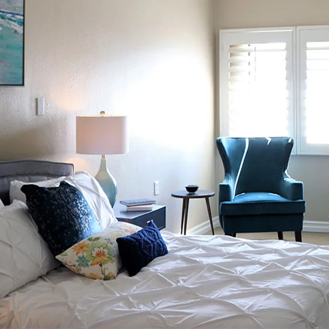 A made bed with armchair and side table